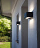 LED Außenwandlampe Gemini IP54 Anthrazit an einer weißen Wand montiert, strahlende Up-&-Down-Lichteffekte.