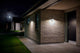 LED Außenwandlampe Rica Round Solar IP44 beleuchtet den Eingang eines modernen Hauses bei Nacht.