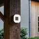 LED Außenwandlampe Ublo 16x16cm IP44 Grau an Holzpfeiler montiert im Außenbereich.