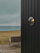 LED Außenwandlampe Valopin IP54 an einer Außenwand mit sichtbarem Meer im Hintergrund.
