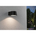 LED Außen Wandleuchte Capea Anthrazit IP44 an einer Wand, strahlt warmes Licht im Außenbereich aus.