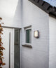 LED Außenwandleuchte Farell mit Sensor IP44 Edelstahl an einer weißen Hauswand montiert.