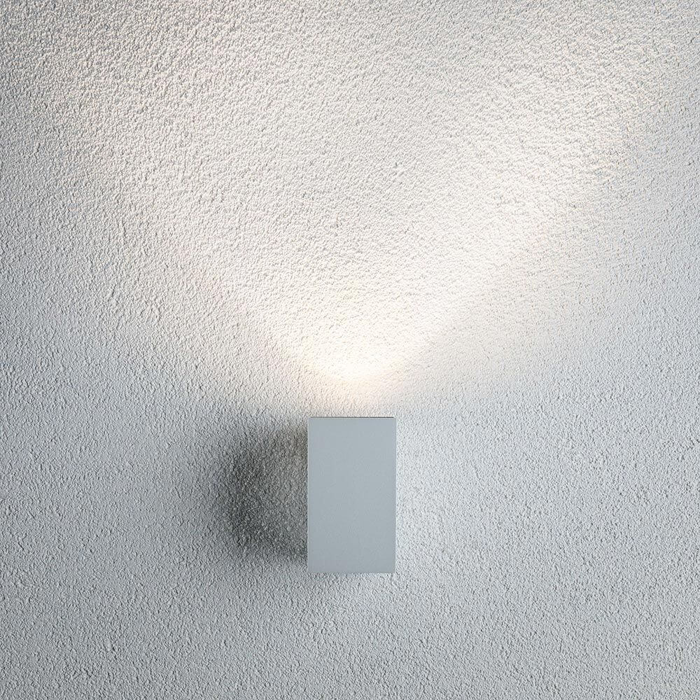 LED Außenwandleuchte Flame Weiß, Metall an einer strukturierten Wand installiert, projiziert attraktives Licht.