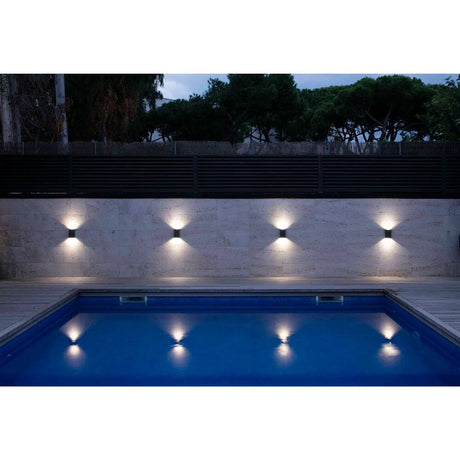 LED Außenwandleuchte LING 6W 4000K IP54 Dunkelgrau beleuchtet den Poolbereich am Abend.
