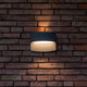 LED Außenwandleuchte Lotus IP54 Anthrazit an Ziegelwand mit warmweißem Licht