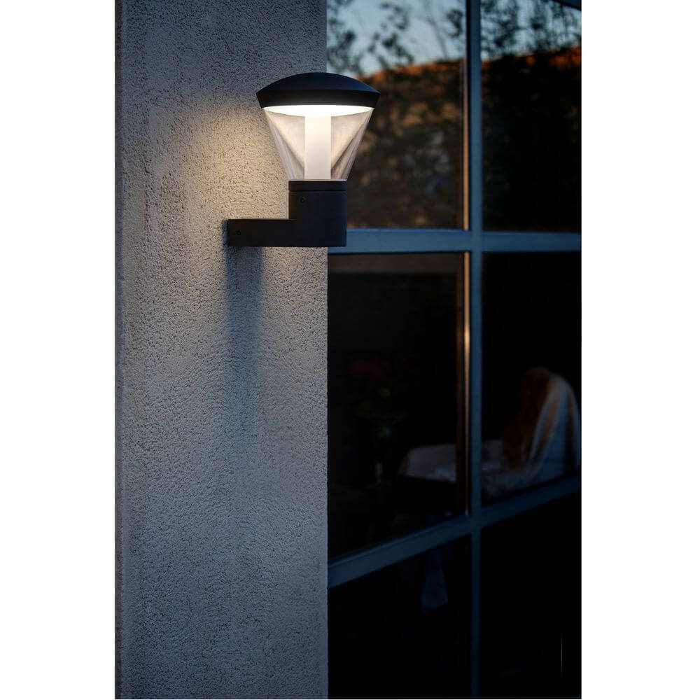 LED Außenwandleuchte SHELBY IP44 Dunkelgrau an einer Wand befestigt, leuchtend bei Dämmerung.