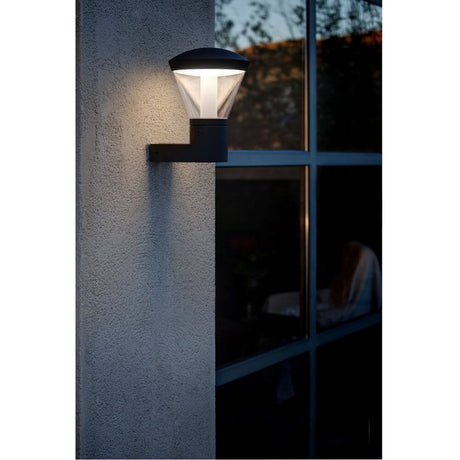 LED Außenwandleuchte SHELBY IP44 Dunkelgrau an einer Wand befestigt, leuchtend bei Dämmerung.