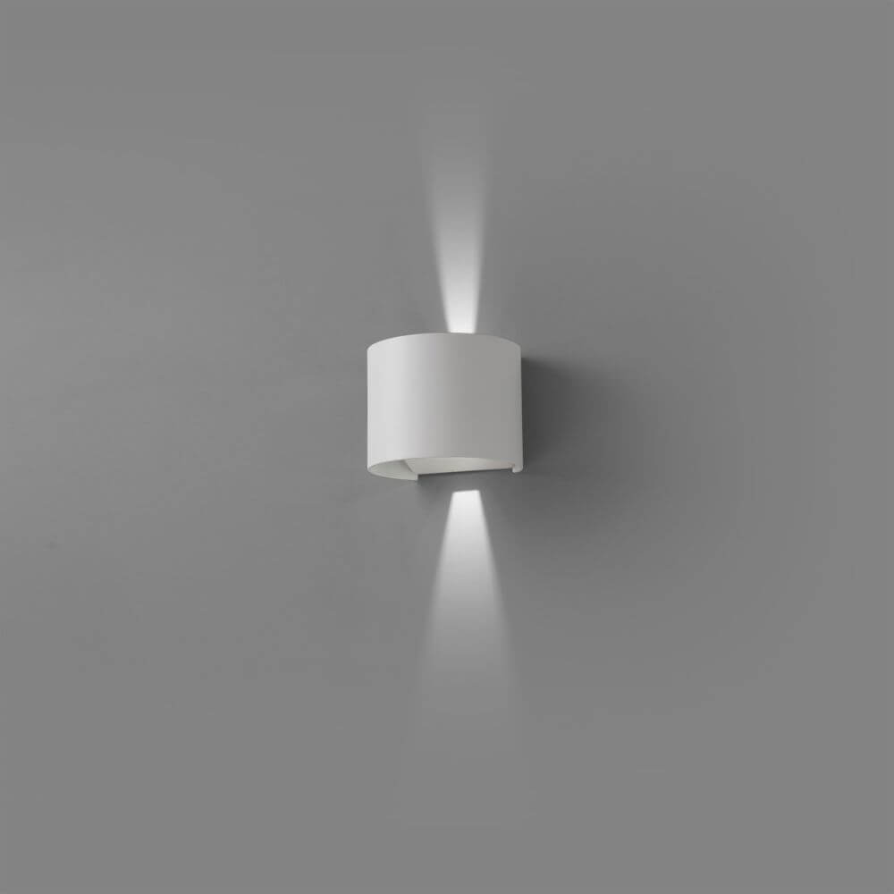LED Außenwandleuchte SUNSET 2x3W 3000K IP54 Weiß an einer grauen Wand montiert, strahlt sanftes Licht aus.