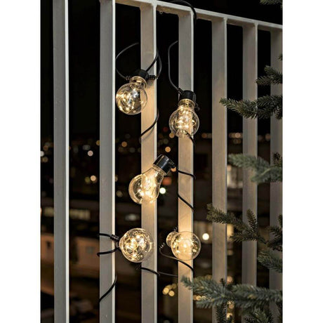 LED Tropfen Biergartenkette klar 50 Dioden Bernstein IP44 an einem Balkon angebracht bei Nacht.