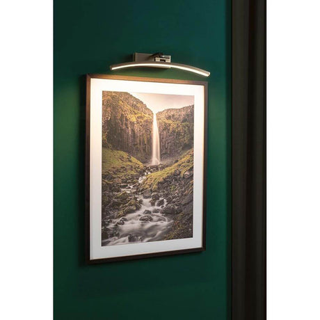LED Mirror & picture light Bento old brass illuminates a work of art in a modern setting.