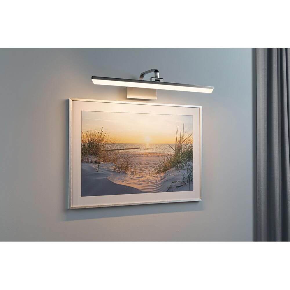 LED Spiegel-& Bilderleuchte Renan 60cm über einem Kunstwerk an der Wand montiert, optimal für Beleuchtung.