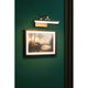 LED Spiegel-& Bilderleuchte Renan Messing-Antik beleuchtet ein Kunstwerk an der Wand.