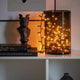 LED Büschellichterkette Cluster Schwarz in einem dekorativen Glasbehälter mit warmweißem Licht.