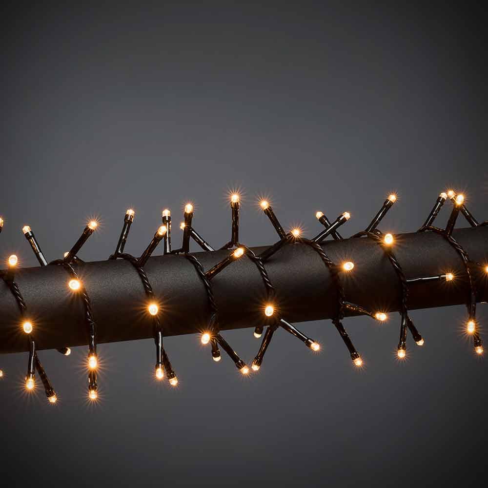 LED Büschellichterkette Cluster Schwarz auf einem schwarzen Rohr, leuchtende Lichter für festliche Dekoration.