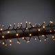 LED Büschellichterkette Cluster Schwarz auf einem schwarzen Rohr, leuchtende Lichter für festliche Dekoration.