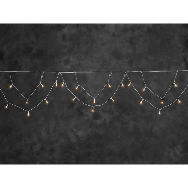 LED Dachrinnenlichterkette Bogenform 96 bernsteinfarbene Dioden IP44 auf grünem Hintergrund.