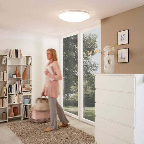 LED Deckenleuchte Giron Ø 100cm + Fernbedienung Weiß in modernem Wohnraum mit Frau und Bücherregal.