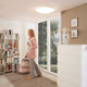 LED Deckenleuchte Giron Ø 100cm + Fernbedienung Weiß in modernem Wohnraum mit Frau und Bücherregal.