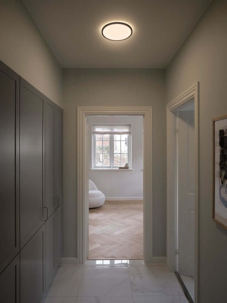 Moderne LED Deckenleuchte Oja 29 im Flur, sorgt für funktionales Licht und dekorativen Gegenlichteffekt.