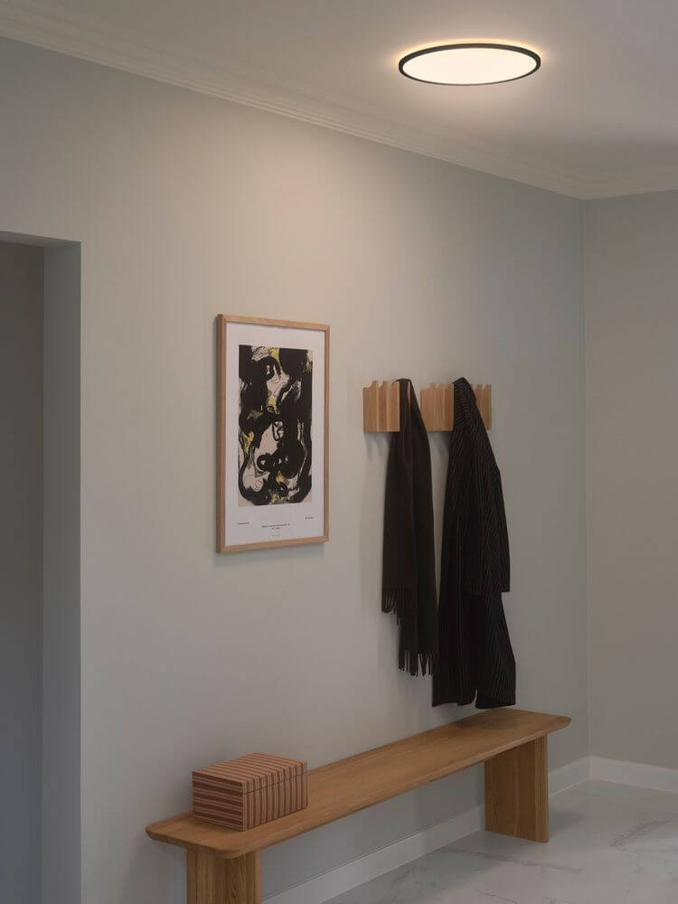 LED Deckenleuchte Oja 42 3-Stufen IP54 in modernem Raum mit Kunstwerk und Garderobe