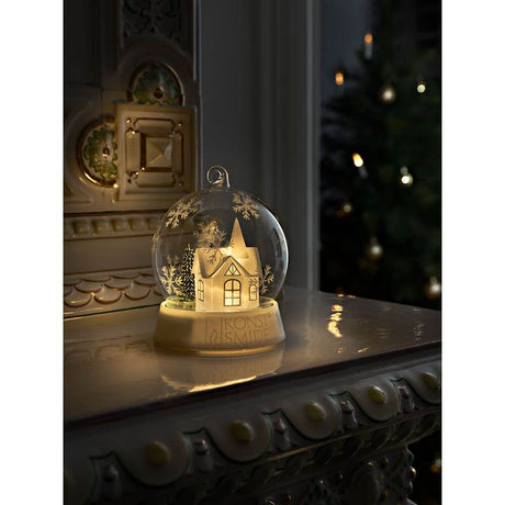 LED Decorative glass ball house warm white battery-operated on a table in a festive setting with warm light.