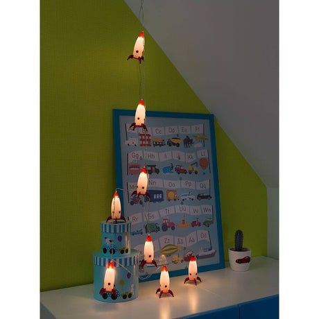 LED Dekolichterkette Raketen Maße: B: 8cm H: 11cm 8 Warmweiße Dioden in einem Raum mit buntem Hintergrund.