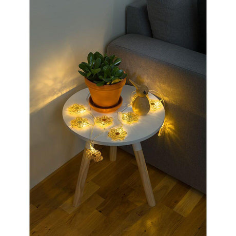 LED Dekolichterkette goldfarbene Metallblumen 10 Warmweiße Dioden batteriebetrieben auf einem Tisch mit Pflanze.