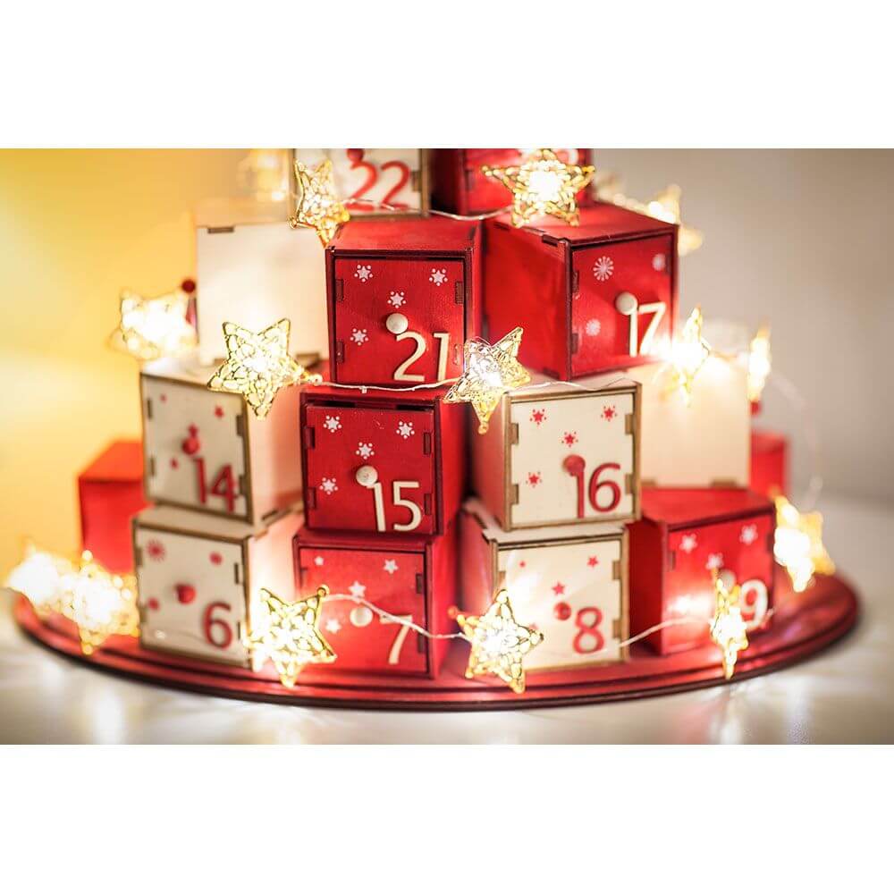 LED Dekolichterkette goldfarbene Metallsterne 20 Warmweiße Dioden batteriebetrieben auf Adventskalender mit roten und weißen Kästchen.
