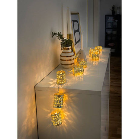 LED Dekolichterkette goldfarbene Metallzylinder 10 Warmweiße Dioden batteriebetrieben auf einem Sideboard.