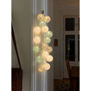 LED Decorative string lights with large light blue/grey/white cotton balls, 16 warm white diodes on an indoor wall.