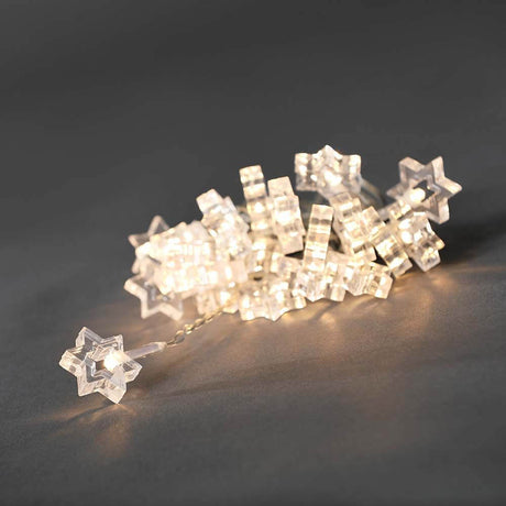 LED Dekolichterkette klare Sterne 24 Warmweiße Dioden, filigrane, leuchtende Sterne auf dunklem Hintergrund.