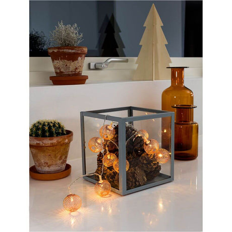 LED decorative string lights copper-colored metal balls 10 warm-white diodes battery-operated arranged in a decorative glass vessel.