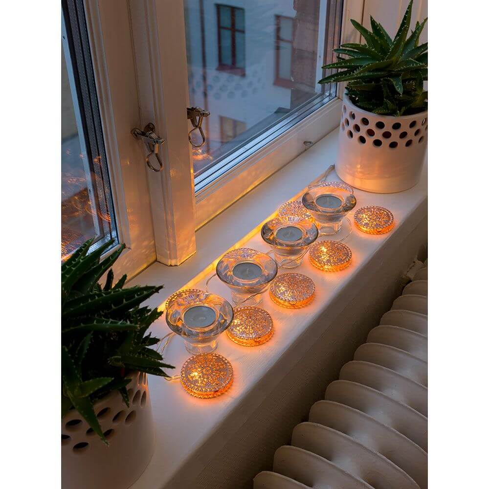 LED Dekolichterkette kupferfarbene Metalltaler 10 Warmweiße Dioden batteriebetrieben auf einem Fensterbrett mit Pflanzen.