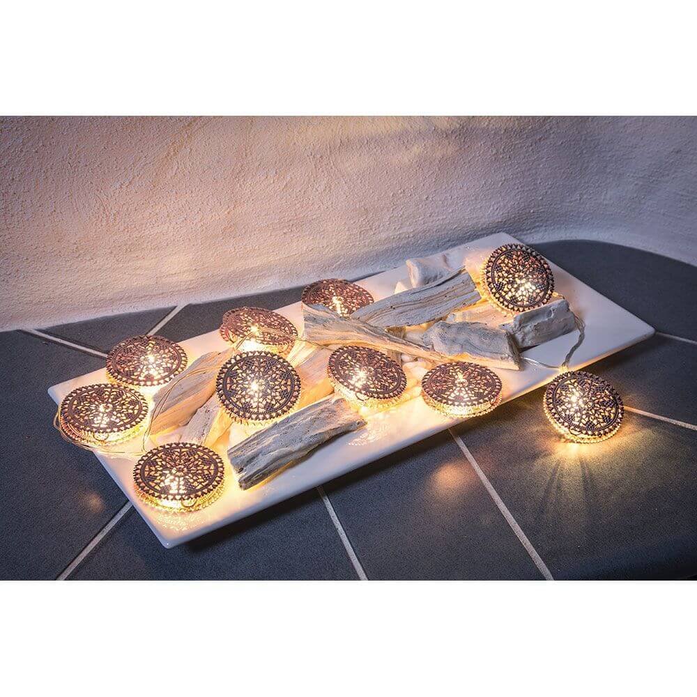 LED Dekolichterkette kupferfarbene Metalltaler 10 Warmweiße Dioden batteriebetrieben auf einem Dekoteller.
