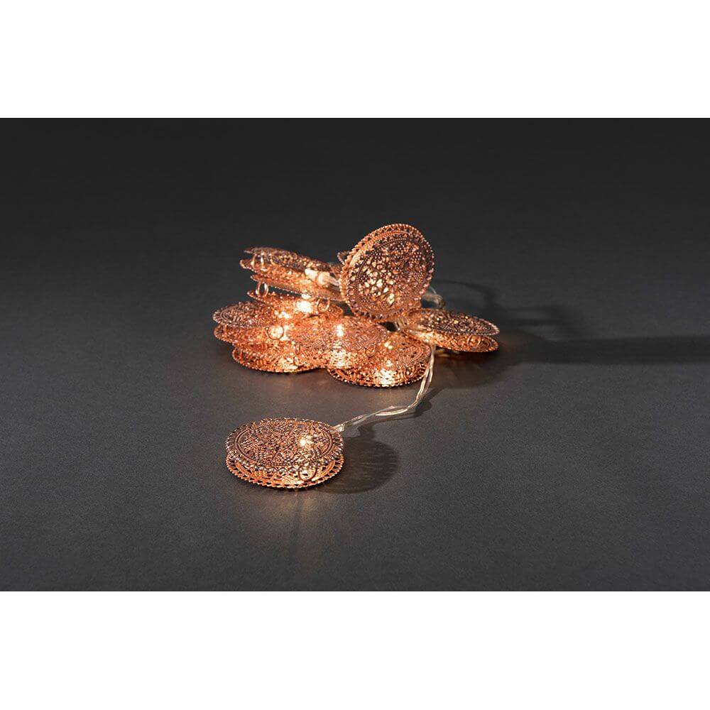 LED Dekolichterkette kupferfarbene Metalltaler 10 Warmweiße Dioden batteriebetrieben auf dunklem Hintergrund.