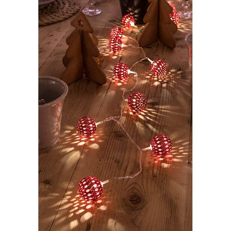 LED Decorative string light red metal balls 24 warm white diodes on a rustic table, perfect for festive decoration.