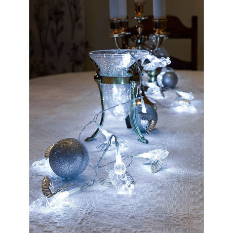 LED Decorative light chain with silver-colored angels, 24 cool white diodes, decoratively placed on a table with candles and a glass jug.