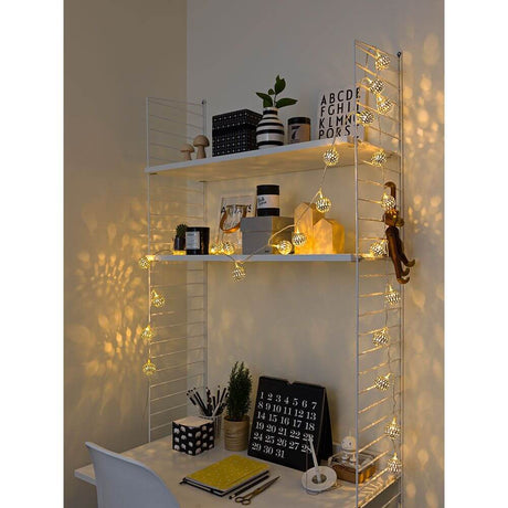 LED Dekolichterkette silberne Metallbälle 24 Warmweiße Dioden 24V Innentrafo mit stimmungsvollem Licht auf einem Regal.