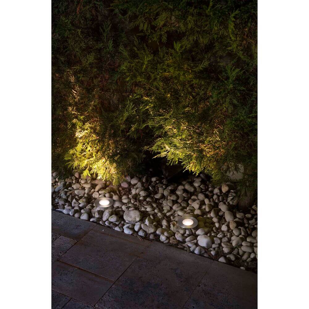 LED innfellingslampe GRUND 36° 3000K IP67 nikkelmatt, installert i hagen, gir et mykt lys på steiner.