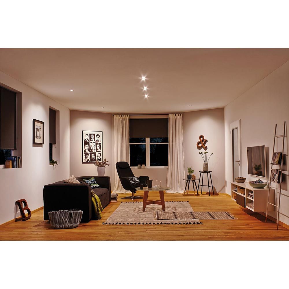 Modernes Wohnzimmer mit LED Einbauleuchten, schwarzem Sofa und stilvoller Einrichtung in sanften Farben.