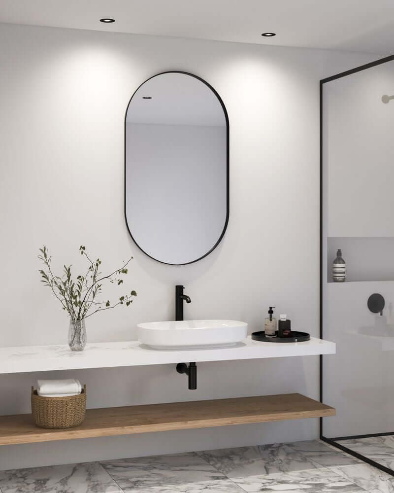 Modernes Badezimmer mit ovalem Spiegel, Waschbecken und minimalistischer Dekoration.