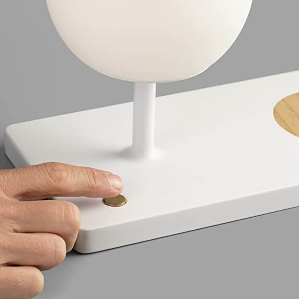 LED Glas Tischlampe NIKO mit induktiver Handy Ladestation, Benutzer schaltet die Lampe ein.