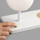 LED Glas Tischlampe NIKO mit induktiver Handy Ladestation, Benutzer schaltet die Lampe ein.