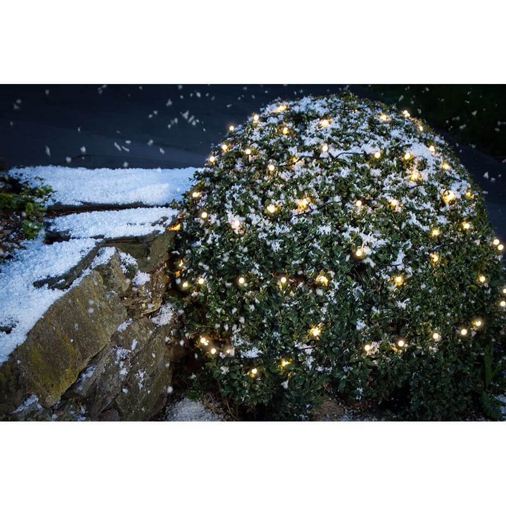 LED Globelichterkette runde Dioden 160 Warmweiße Dioden IP44 auf einem schneebedeckten Busch im Garten.