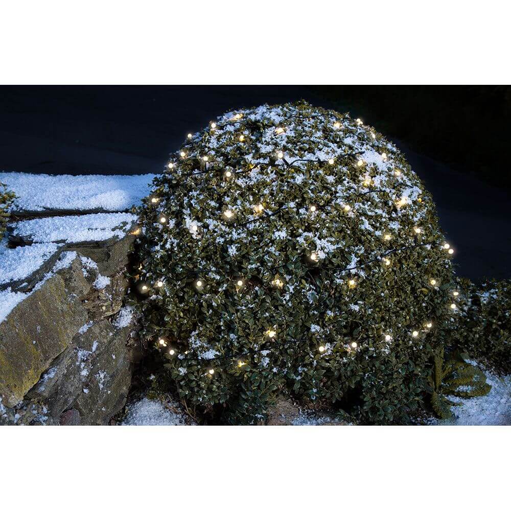 LED Globelichterkette runde Dioden 160 Warmweiße Dioden IP44 auf einem winterlichen Strauch im Schnee.