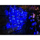 LED Globelichterkette runde Dioden 80 blaue Dioden IP44 an einer Wand mit blauen Lichtern über Blumen.
