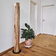 LED Holz-Stehleuchte Lucerna 160cm Satin Nussbaum steht neben einer Pflanze in einem modernen Raum.