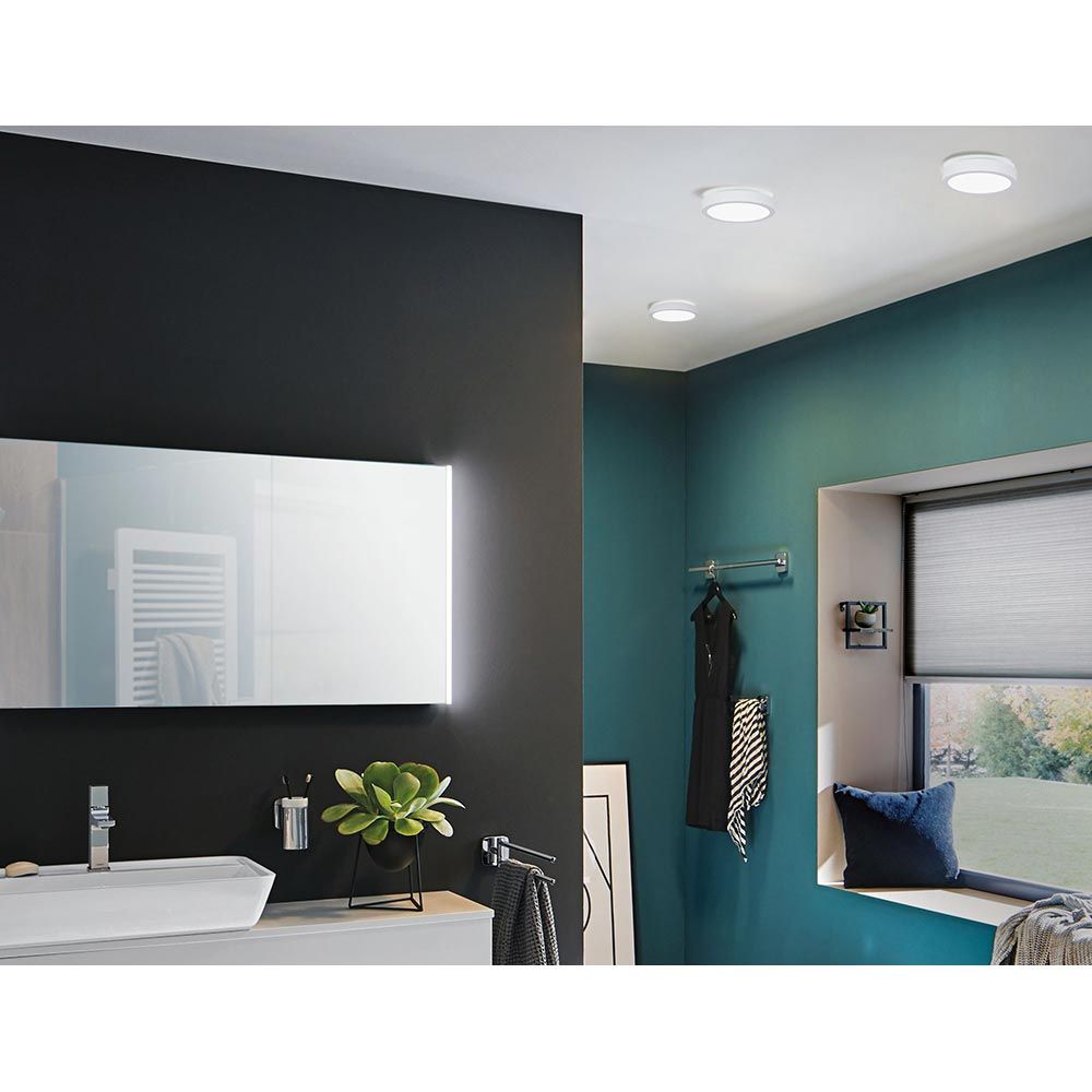 Modernes Badezimmer mit dimmbarem Aviar LED Panel, Spiegel und Fensterbankpflanze.