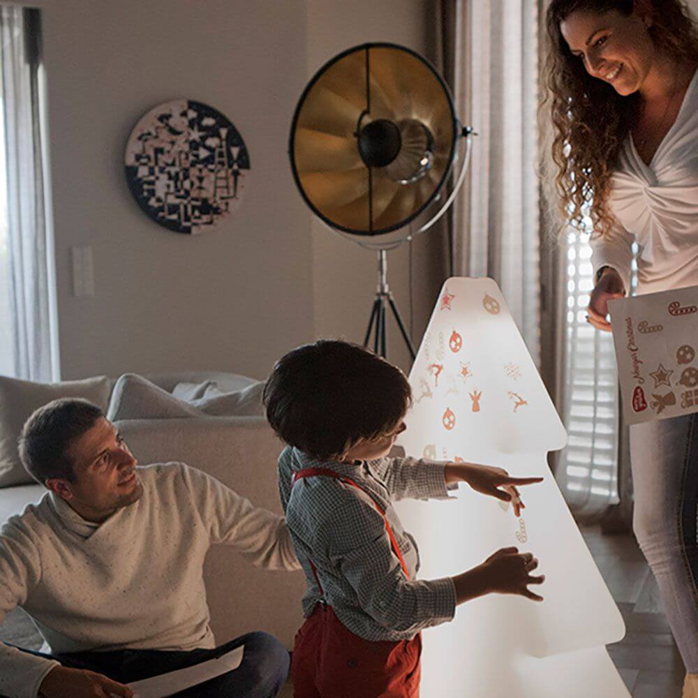 Familie dekoriert den LED Leuchtbaum Pinus 100cm Akku + Solar IP65 im Wohnzimmer bei gemütlichem Licht.