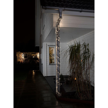 LED Lichterkette mit Lauflicht und verlängertem Steg: 4cm 120 Warmweiße Dioden IP44 dekoriert eine Hauswand bei Nacht.